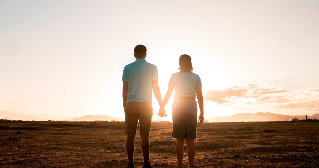 Couple holding hands at sunset, symbolizing emotional connection, trust, and togetherness.
