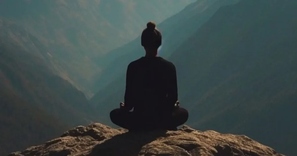 A person meditating on a mountain cliff.