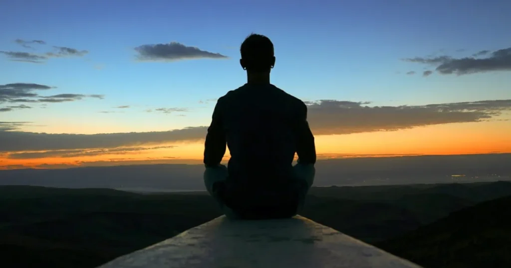 man sitting alone watching sunset in deep thought and reflection