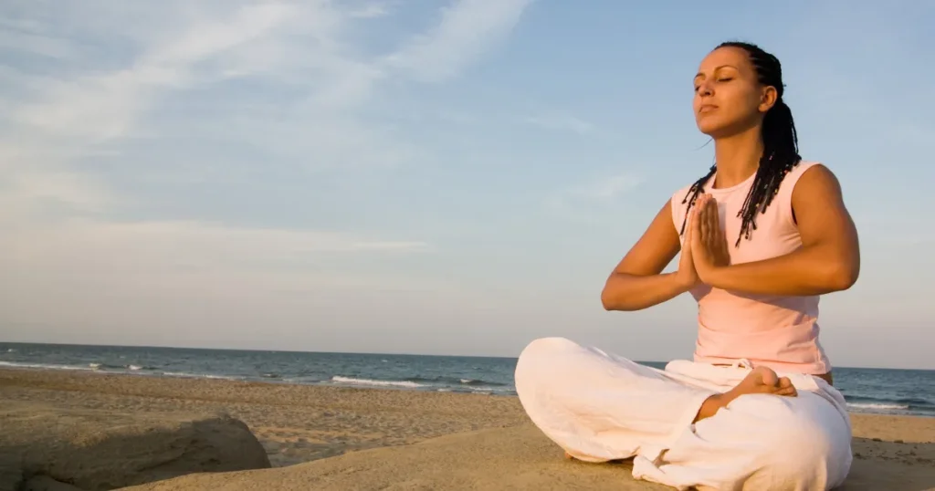 Woman meditating on the beach to build focus and clarity.