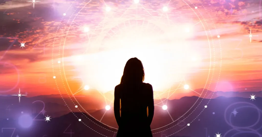 Silhouette of a woman standing before a radiant sunrise.
